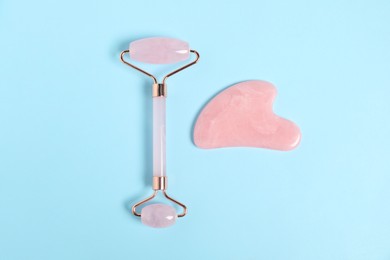 Photo of Face roller and gua sha tool on light blue background, top view