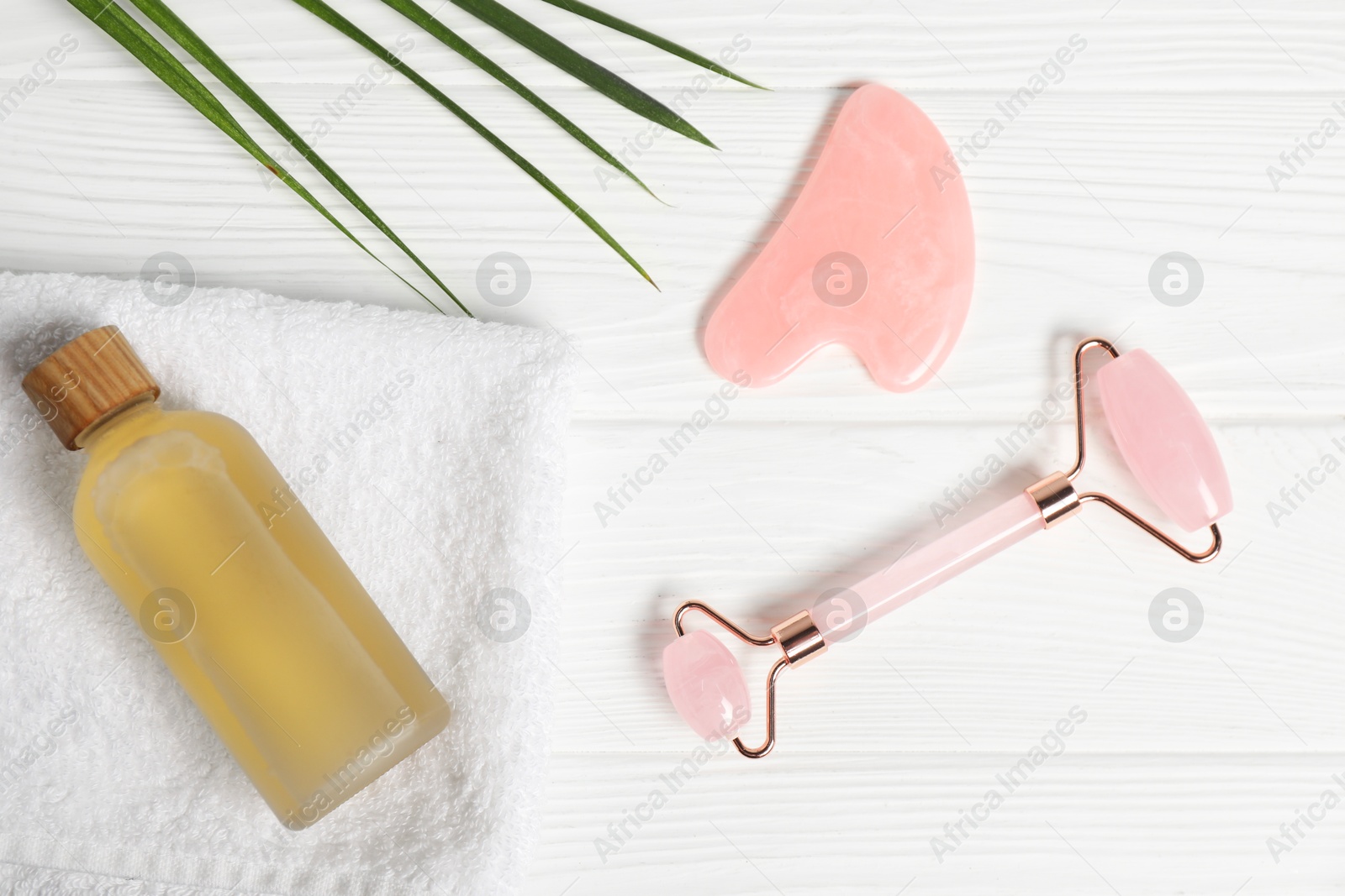 Photo of Face roller, gua sha tool and cosmetic product on white wooden background, flat lay