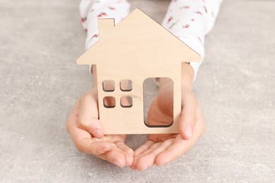 Photo of Adoption. Little girl with house figure at grey table, closeup