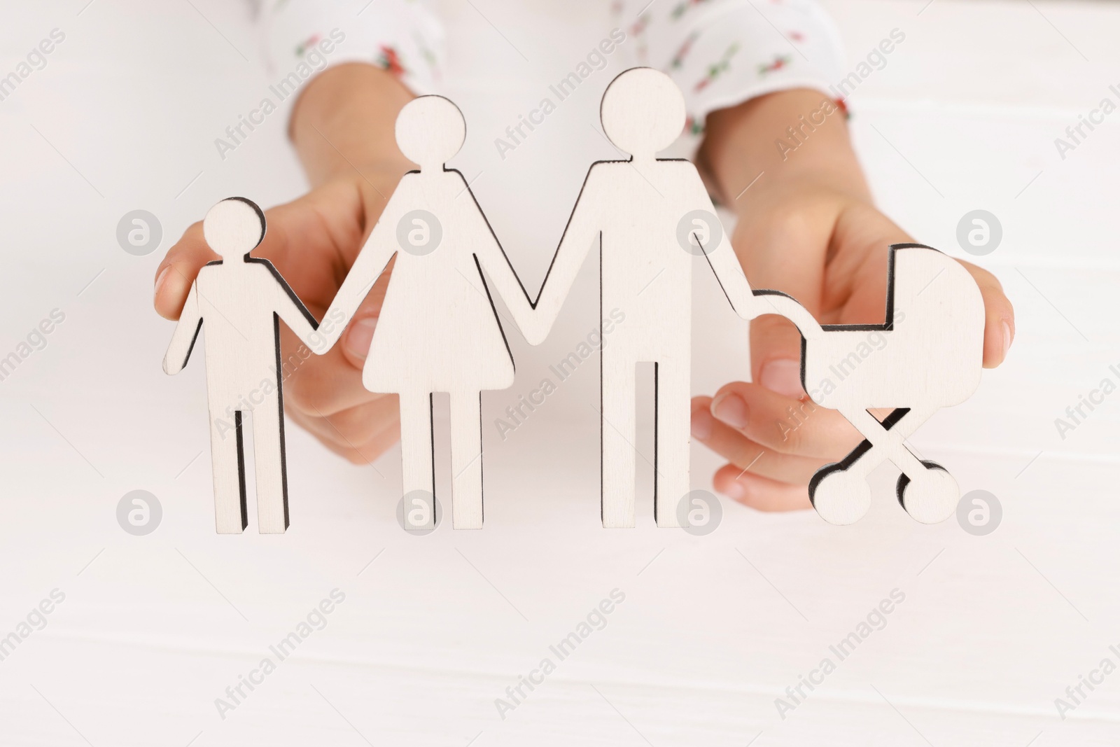 Photo of Adoption. Little girl with figures of family at white table, closeup