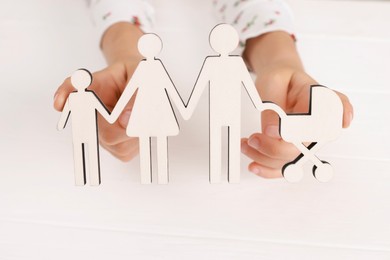 Adoption. Little girl with figures of family at white table, closeup