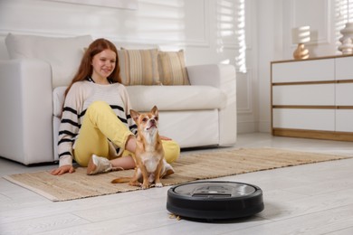 Photo of Teenage girl and her cute Chihuahua dog on robotic vacuum cleaner at home, selective focus