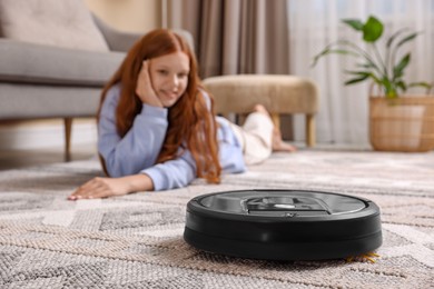 Photo of Teenage girl resting at home while robotic vacuum cleaner vacuuming rug