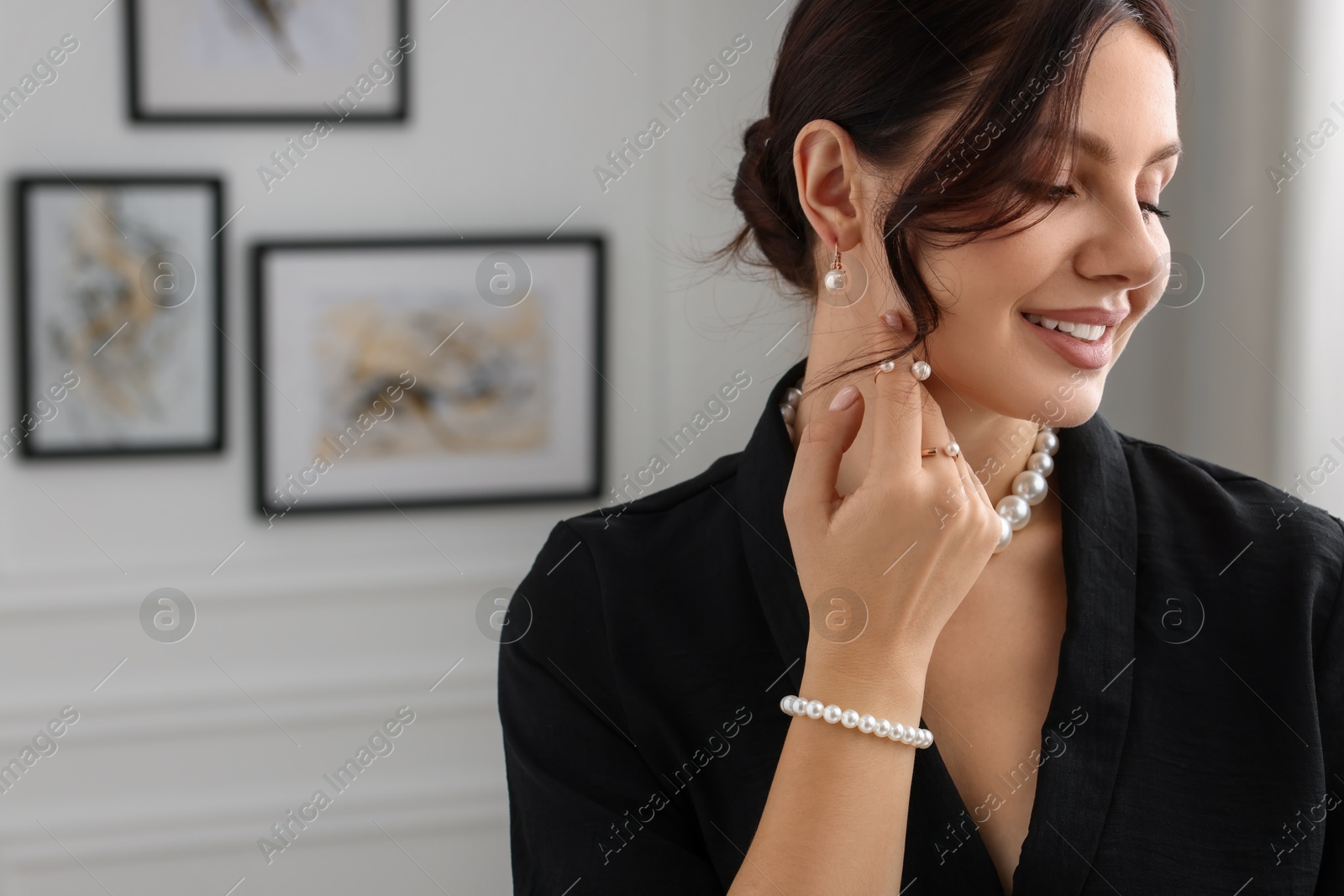 Photo of Beautiful young woman wearing elegant pearl jewelry indoors. Space for text