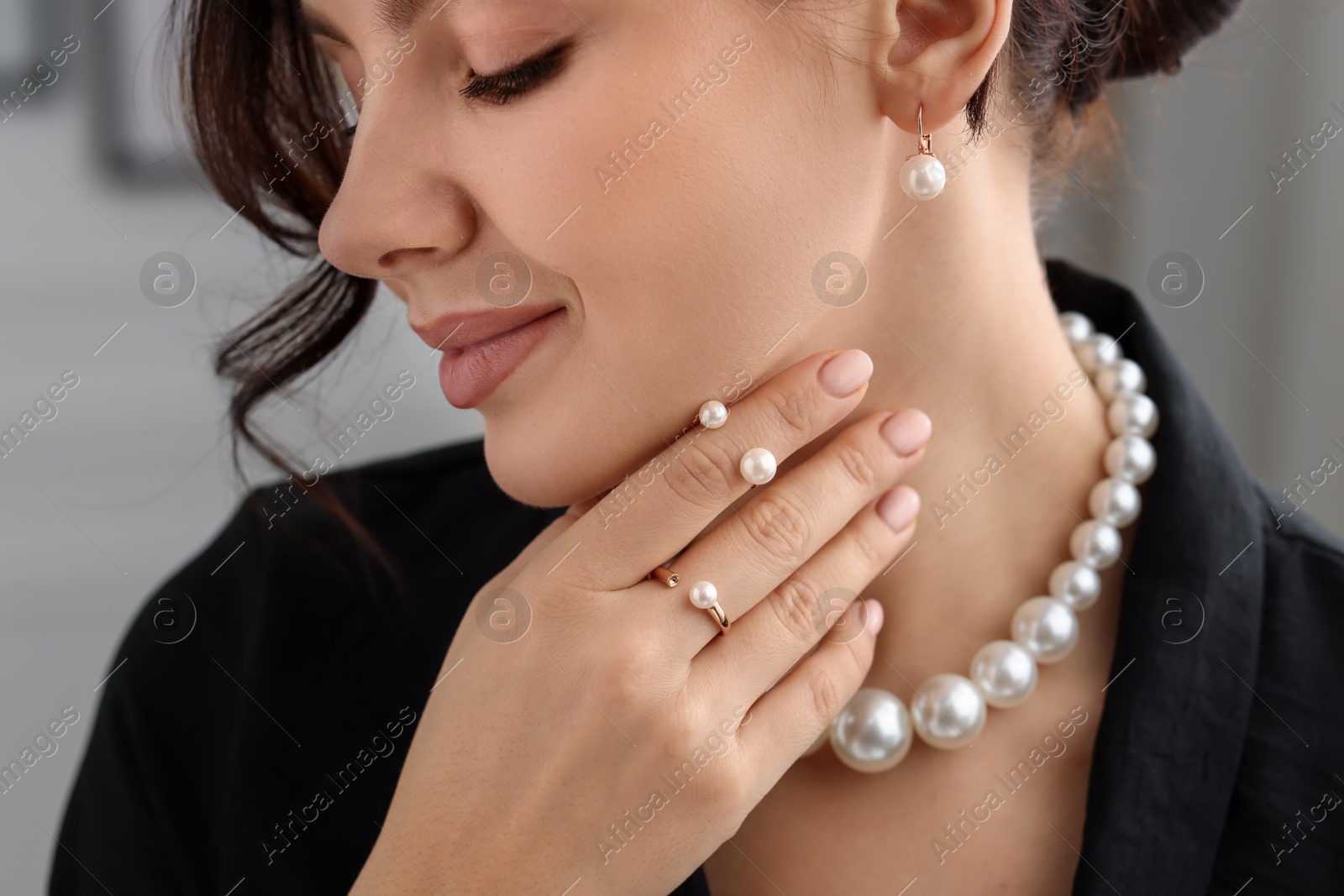 Photo of Young woman wearing elegant pearl jewelry indoors, closeup