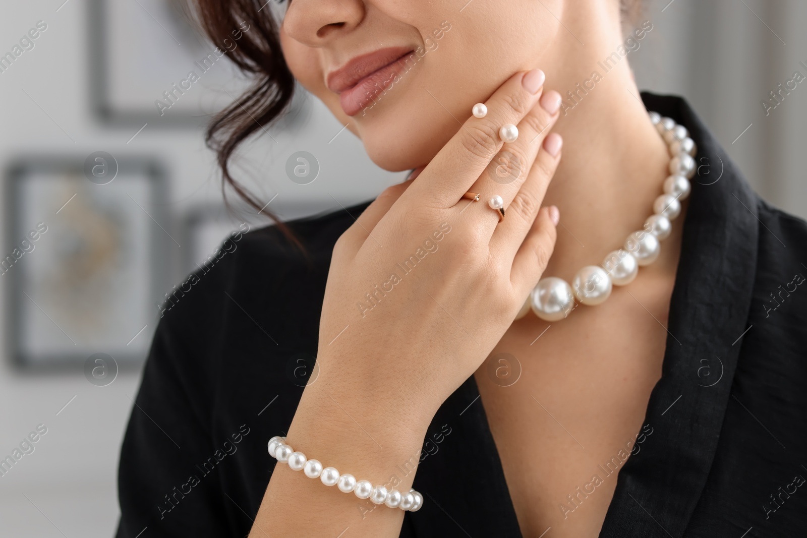 Photo of Young woman wearing elegant pearl jewelry indoors, closeup