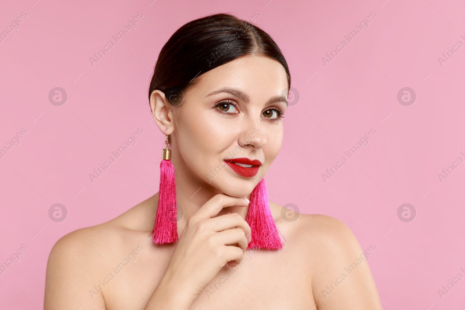 Photo of Beautiful young woman wearing stylish earrings on pink background