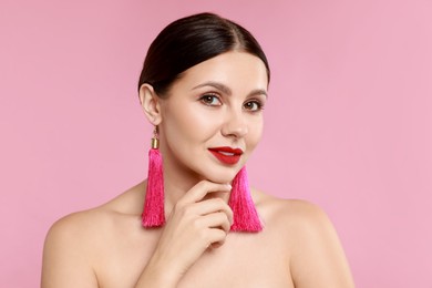 Photo of Beautiful young woman wearing stylish earrings on pink background