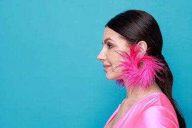 Photo of Beautiful young woman wearing stylish earrings on light blue background. Space for text