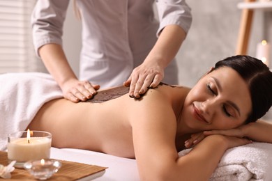 Photo of Woman undergoing chocolate body wrap treatment in spa salon