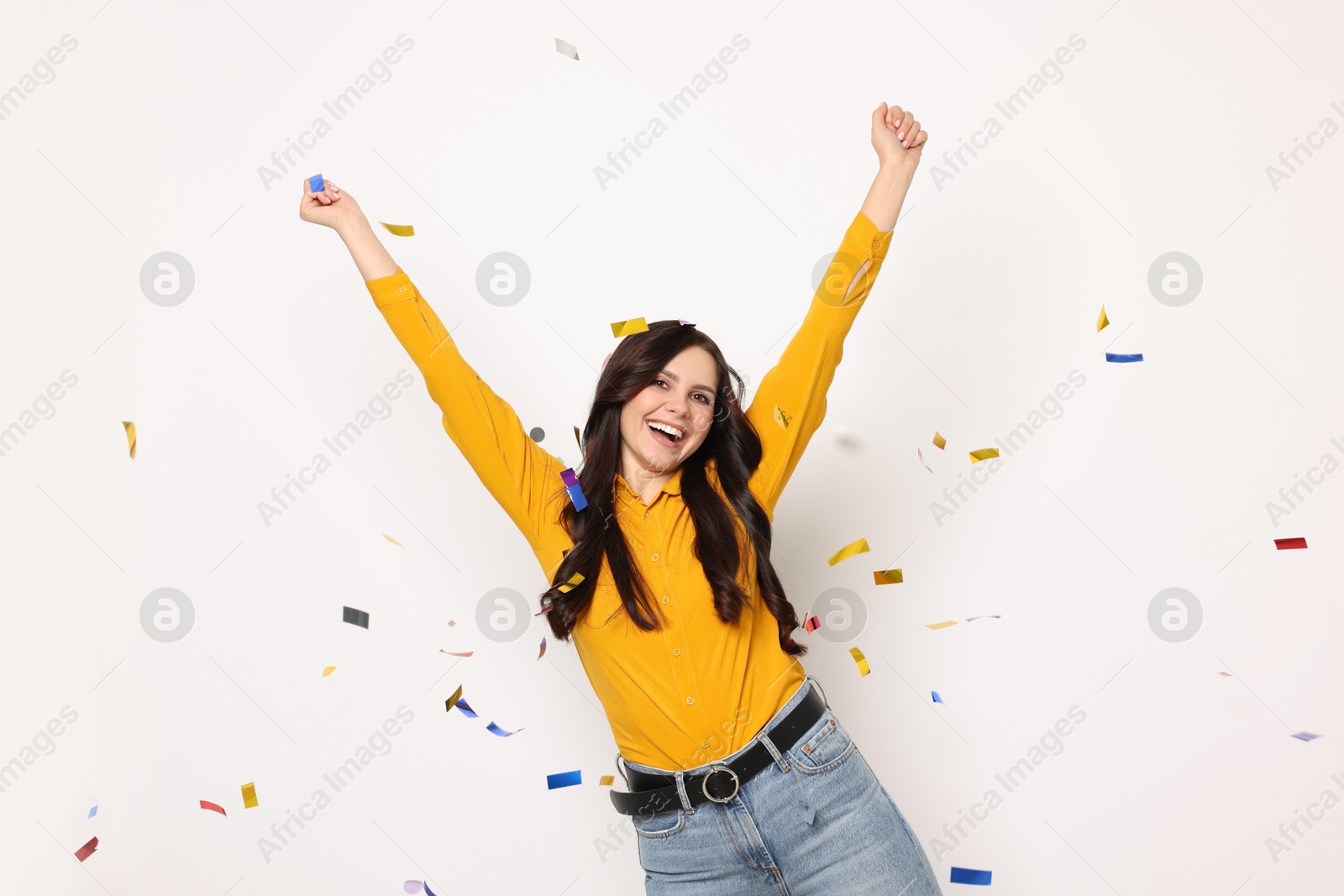 Photo of Happy woman under falling confetti on white background. Surprise party