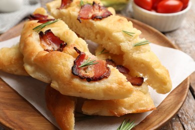 Photo of Slices of delicious focaccia bread with bacon and rosemary on table, closeup