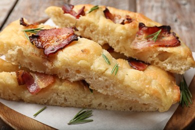 Photo of Slices of delicious focaccia bread with bacon and rosemary on table, closeup