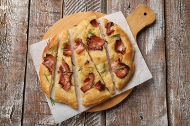 Photo of Slices of delicious focaccia bread with bacon and rosemary on wooden table, top view