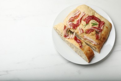 Photo of Pieces of delicious focaccia bread with bacon and rosemary on white marble table, top view. Space for text