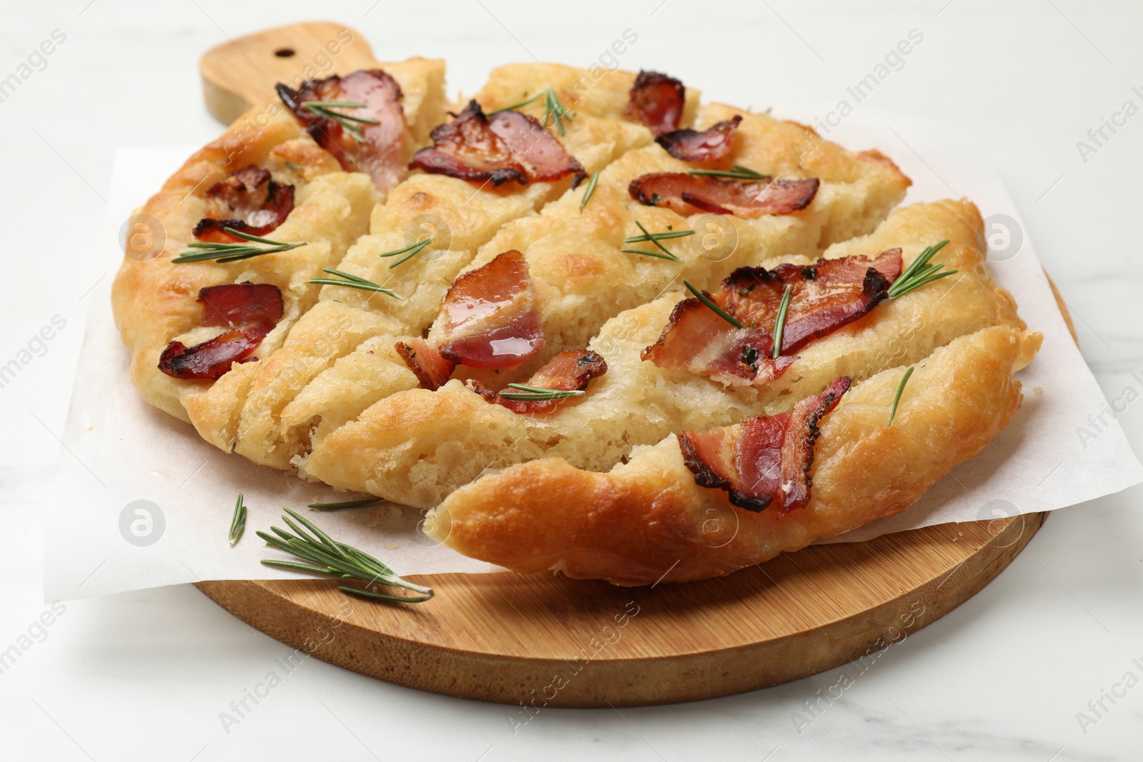 Photo of Slices of delicious focaccia bread with bacon and rosemary on white marble table, closeup