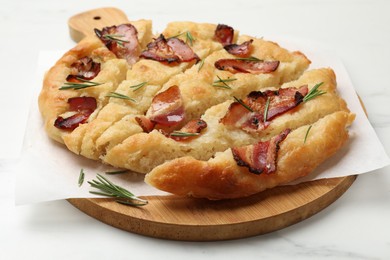 Photo of Slices of delicious focaccia bread with bacon and rosemary on white marble table, closeup