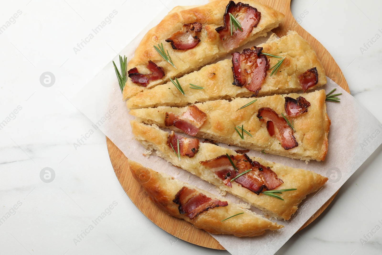 Photo of Slices of delicious focaccia bread with bacon and rosemary on white marble table, top view. Space for text