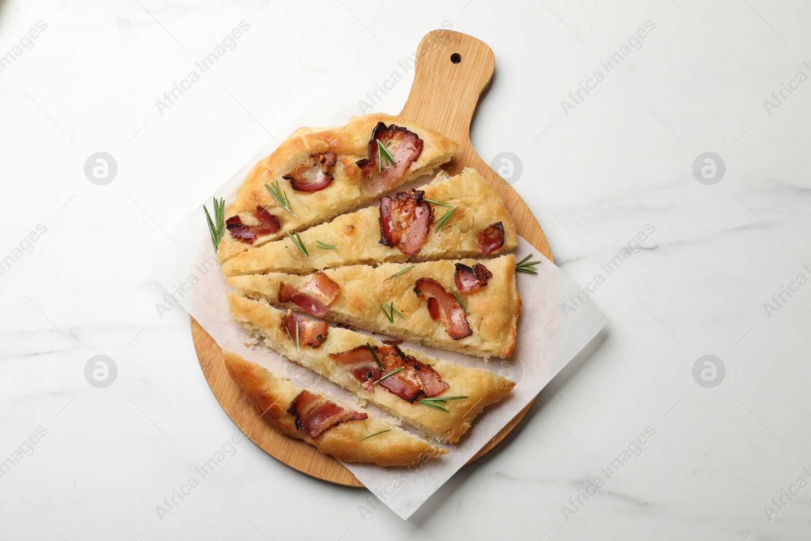 Photo of Slices of delicious focaccia bread with bacon and rosemary on white marble table, top view