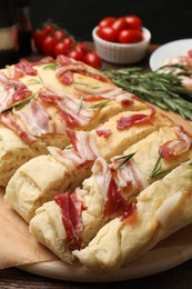 Photo of Slices of delicious focaccia bread with bacon and rosemary on table, closeup