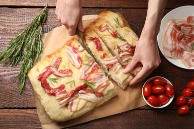 Photo of Woman cutting delicious focaccia bread at wooden table, top view