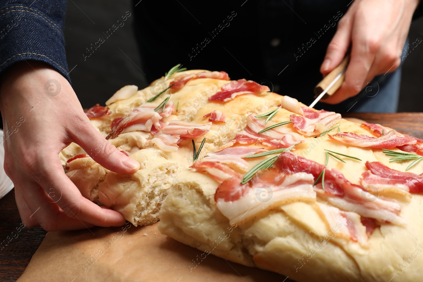 Photo of Woman cutting delicious focaccia bread at table, closeup