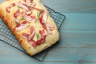 Photo of Delicious focaccia bread with bacon and rosemary on light blue wooden table, top view. Space for text