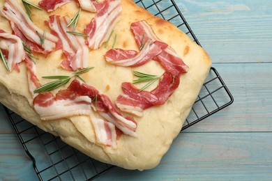 Photo of Delicious focaccia bread with bacon and rosemary on light blue wooden table, top view