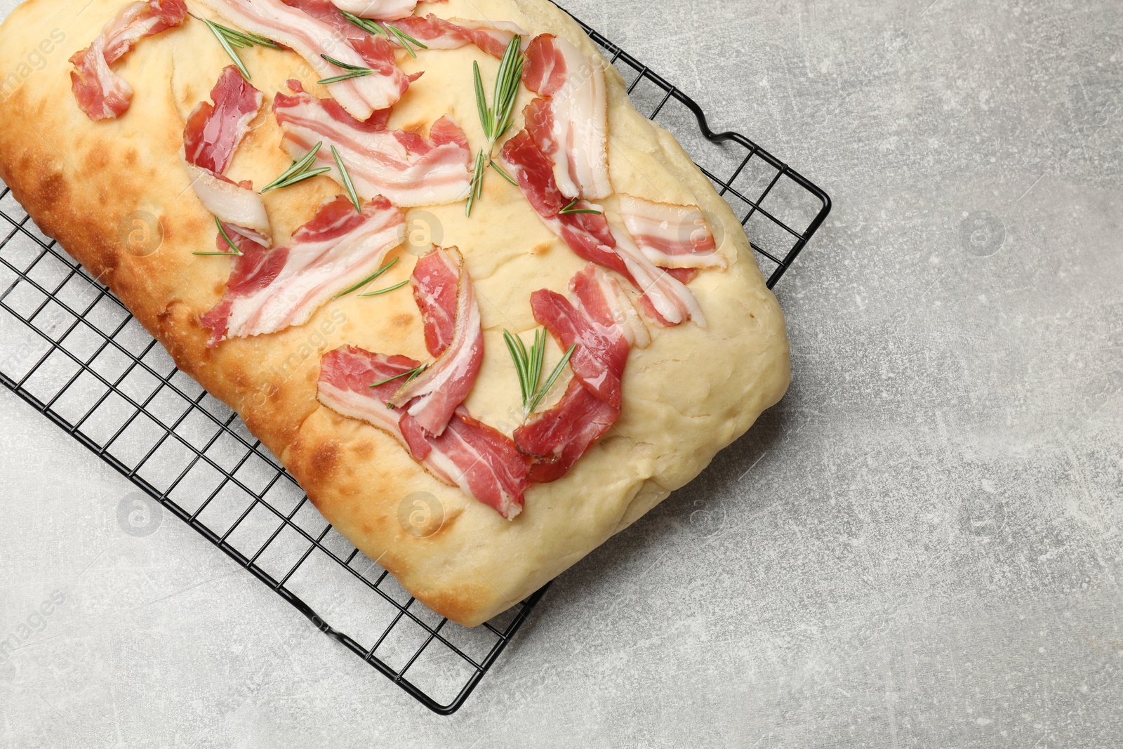 Photo of Delicious focaccia bread with bacon and rosemary on light grey table, top view. Space for text