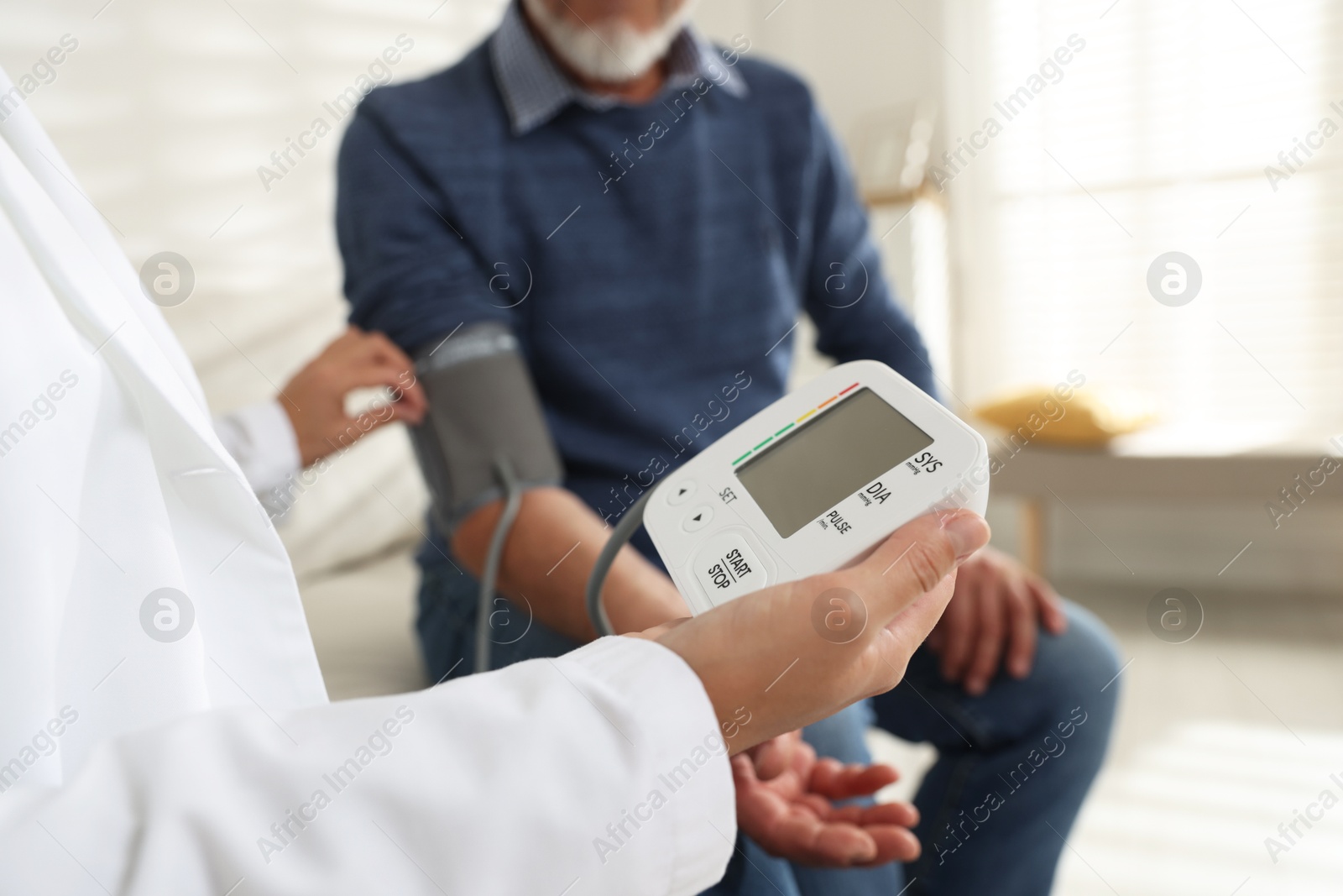 Photo of Doctor measuring patient's blood pressure in hospital, closeup