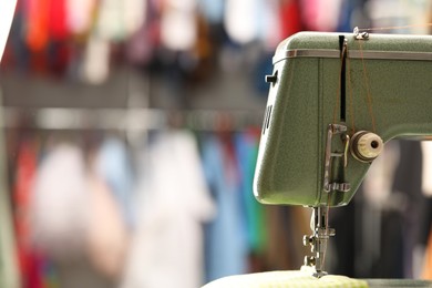 Vintage sewing machine with thread on blurred background, closeup. Space for text