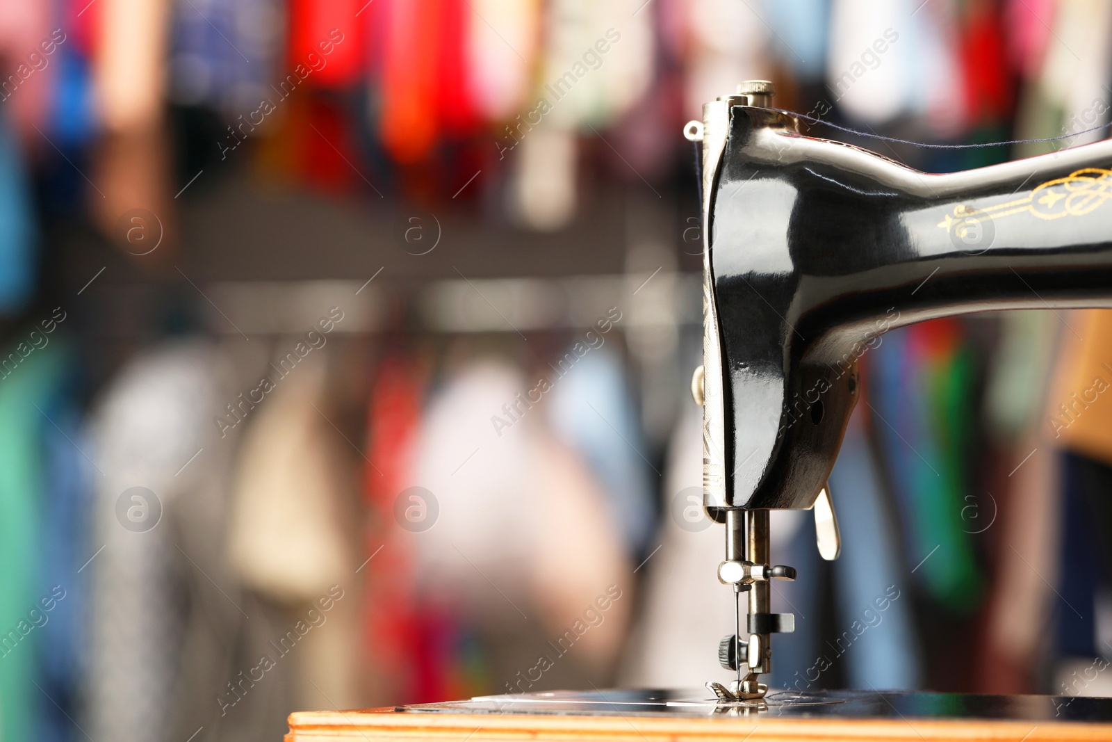 Photo of Vintage sewing machine with thread on blurred background, closeup. Space for text