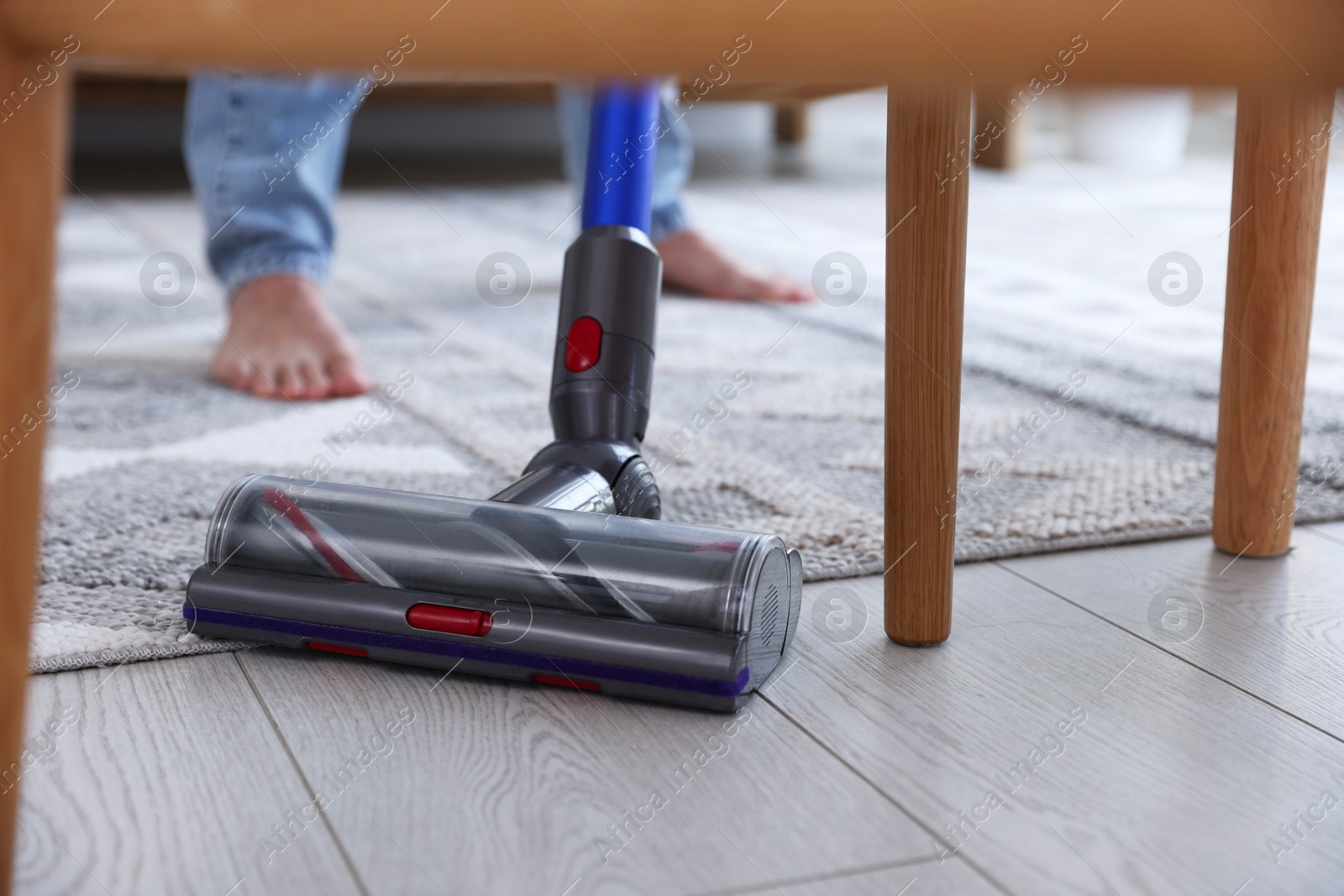 Photo of Man cleaning floor with cordless vacuum cleaner at home, closeup