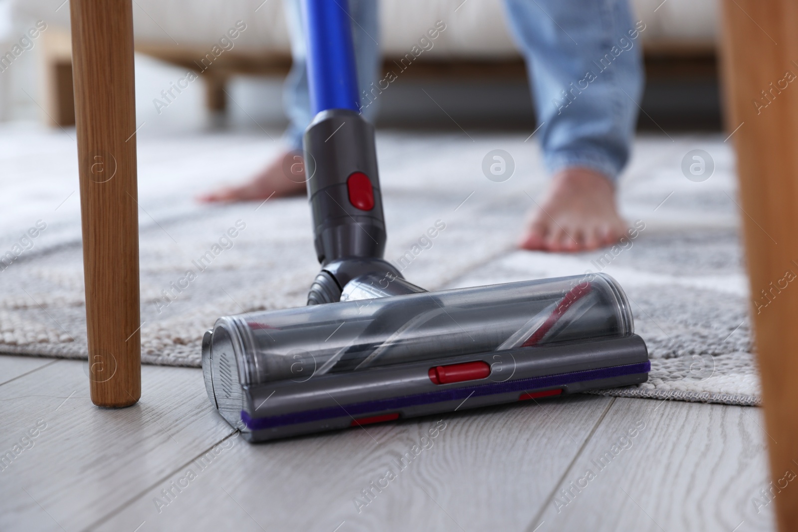 Photo of Man cleaning floor with cordless vacuum cleaner at home, closeup