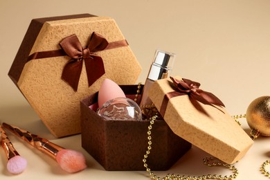 Photo of Cosmetic products as Christmas present. Gift boxes and decor on beige background