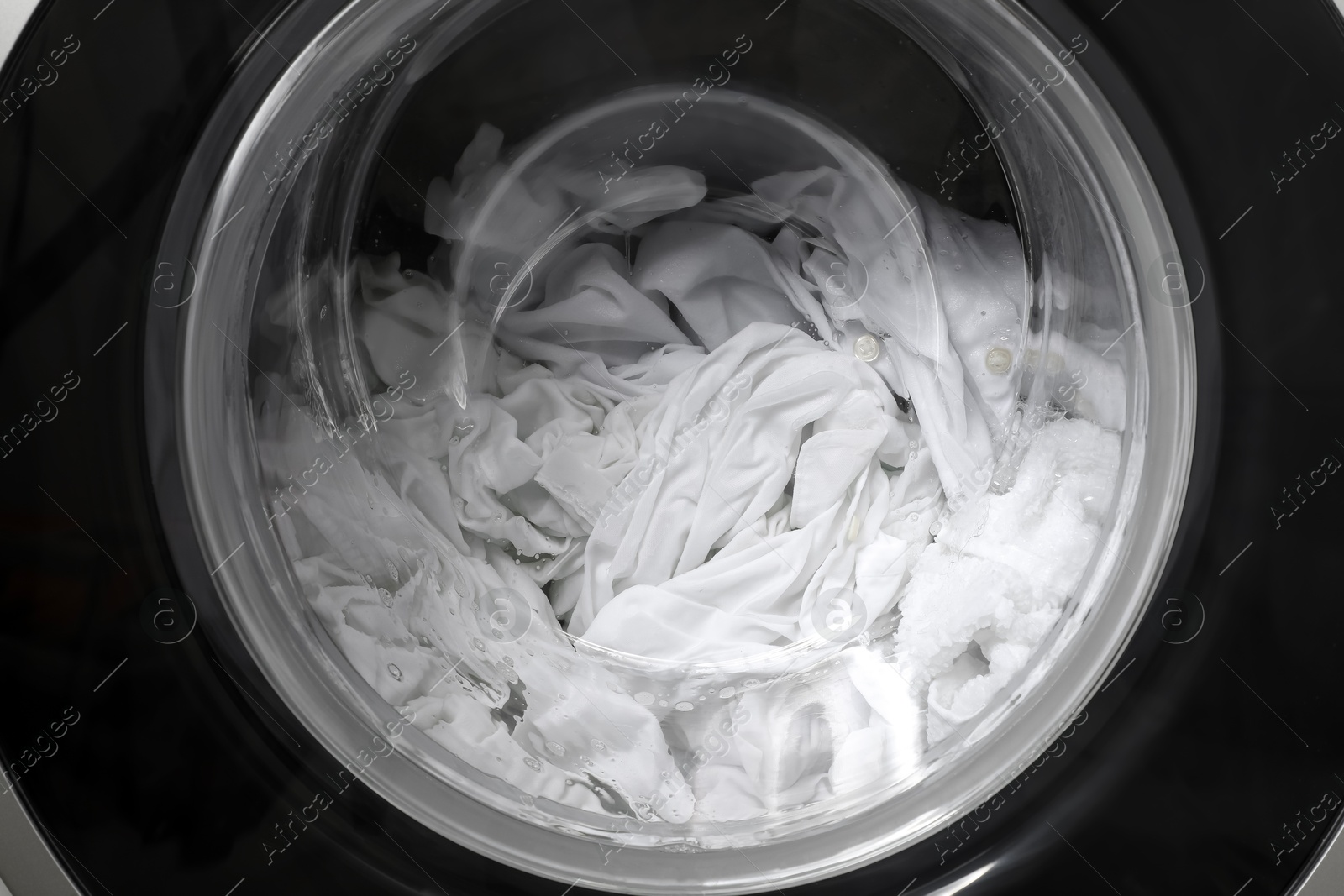 Photo of Washing machine with clothes as background, closeup