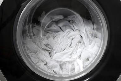 Photo of Washing machine with clothes as background, closeup