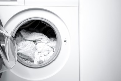 Photo of Open washing machine with clean clothes, closeup. Space for text