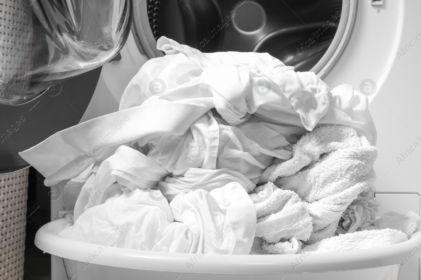 Photo of Basket with laundry near washing machine, closeup