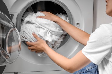 Woman taking clean clothes out of washing machine, closeup