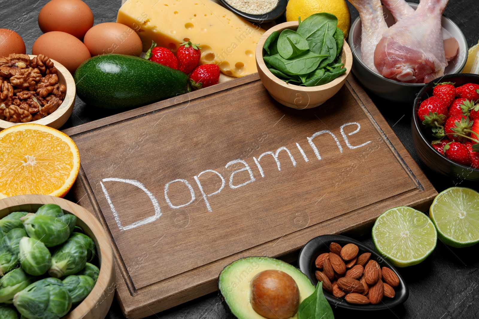 Photo of Wooden board with word Dopamine and different fresh products on grey textured table