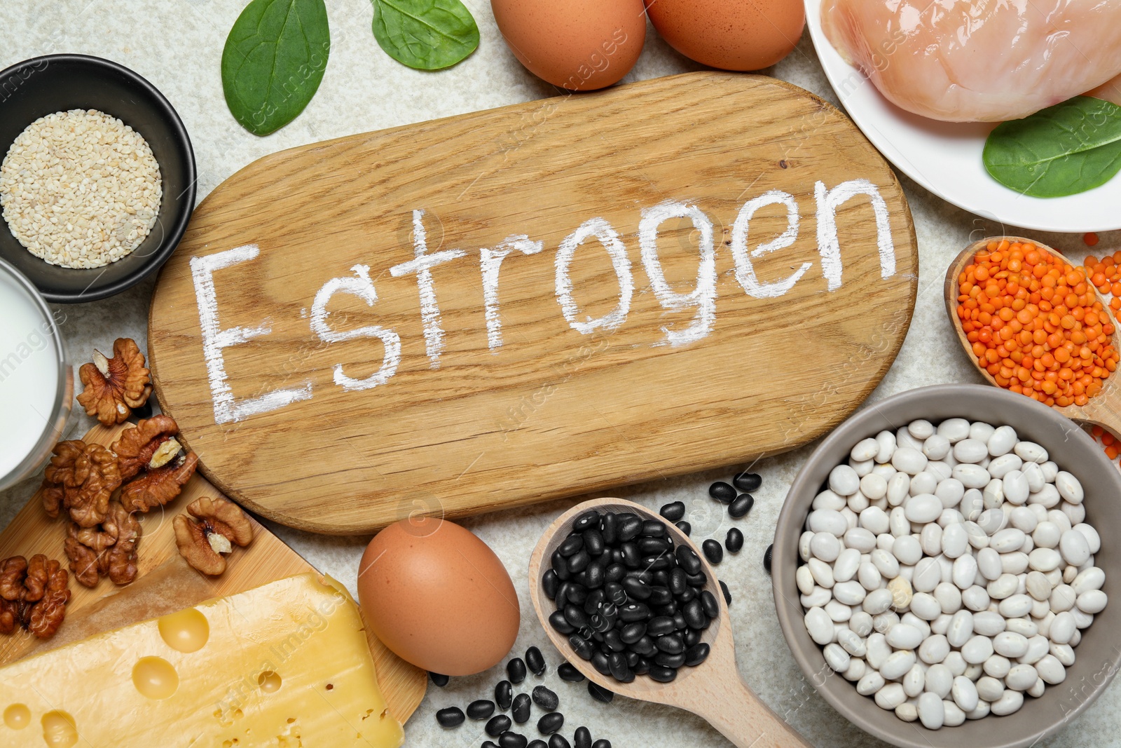 Photo of Wooden board with word Estrogen and different fresh products on light textured table, flat lay