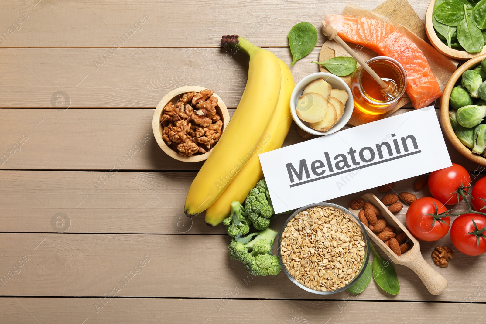 Photo of Word Melatonin and different products on wooden table, flat lay