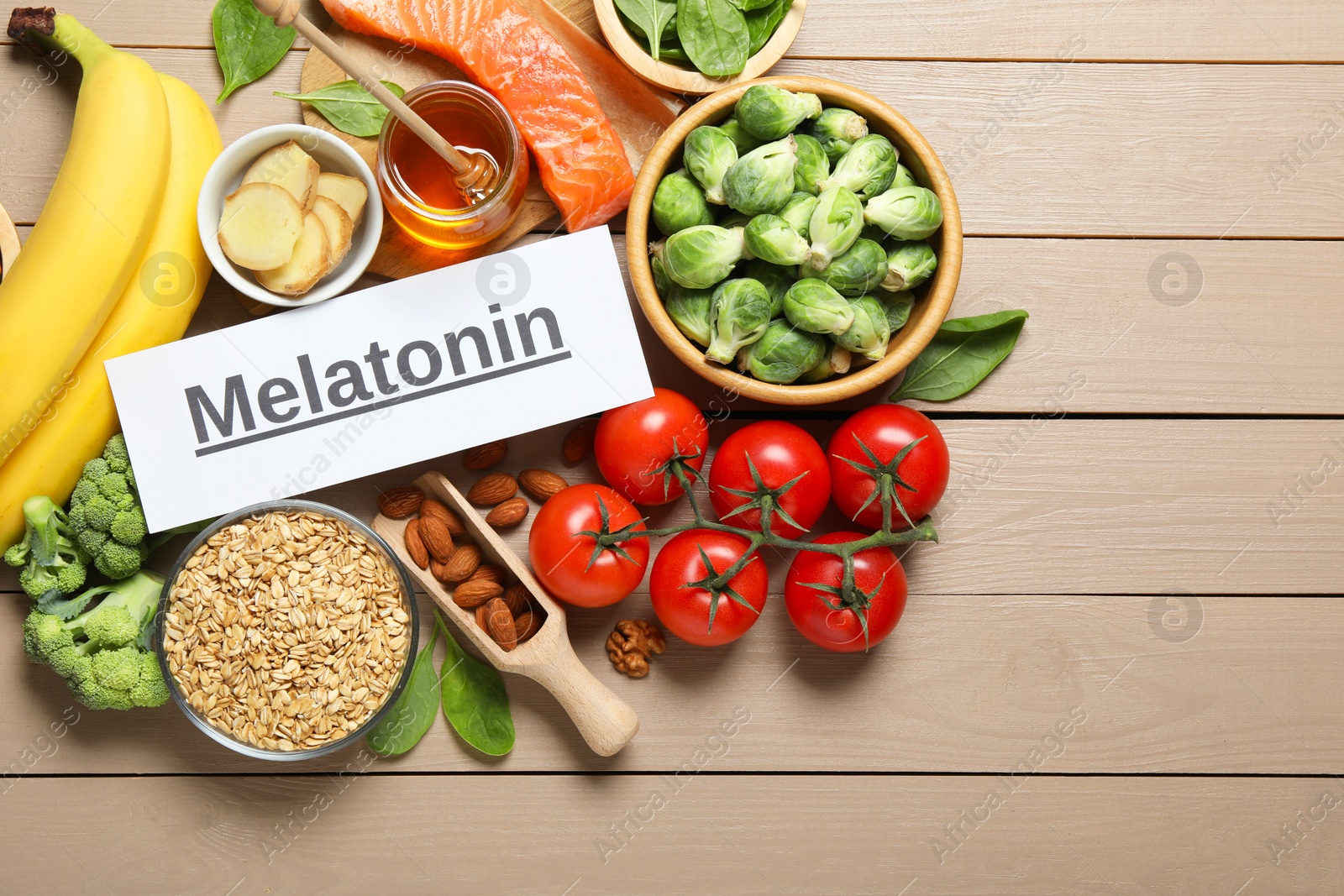 Photo of Word Melatonin and different products on wooden table, flat lay