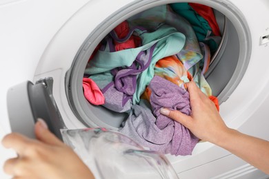 Woman putting dirty laundry into washing machine, closeup