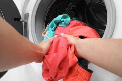 Photo of Woman putting dirty laundry into washing machine, closeup