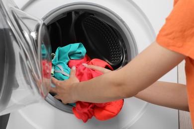 Photo of Woman putting dirty laundry into washing machine, closeup