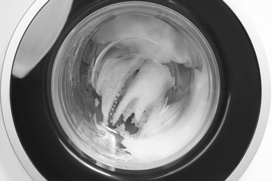 Photo of Washing machine with suds as background, closeup