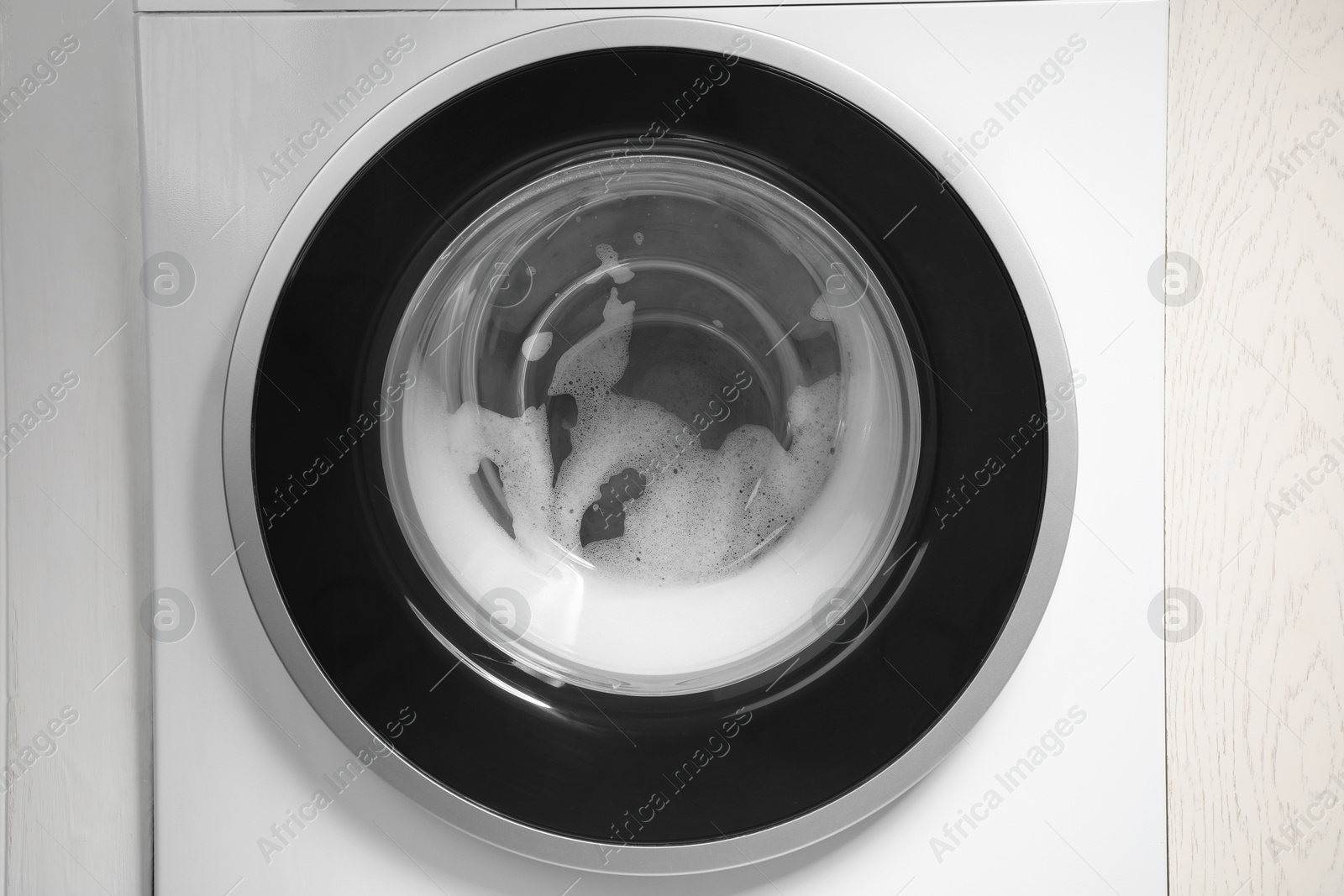 Photo of Washing machine with suds as background, closeup