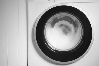 Photo of Washing machine with suds as background, closeup